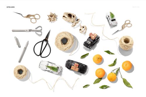 Gift wrapping paper mockup scene with scissors, twine, toy cars, oranges, leaves, and wrapping accessories on white.