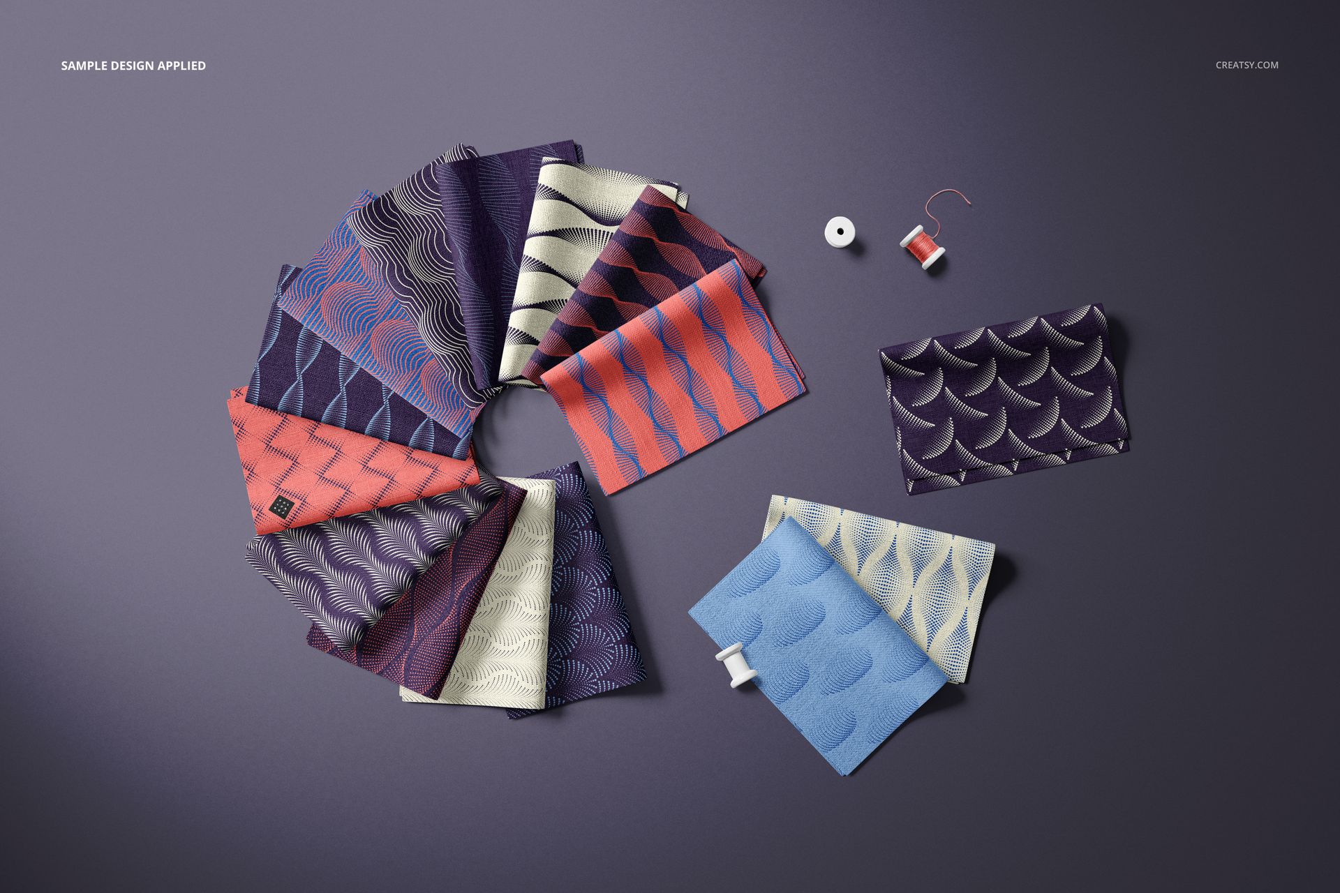 PSD mockup showing multiple folded fabric swatches in a fan-like arrangement, with abstract patterns and sewing props nearby.
