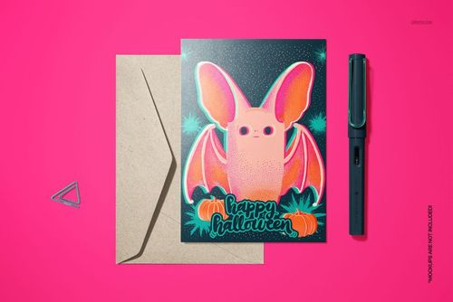 Halloween card mockup with a colorful bat design, pumpkins, and festive text, displayed next to a brown envelope on a pink background.