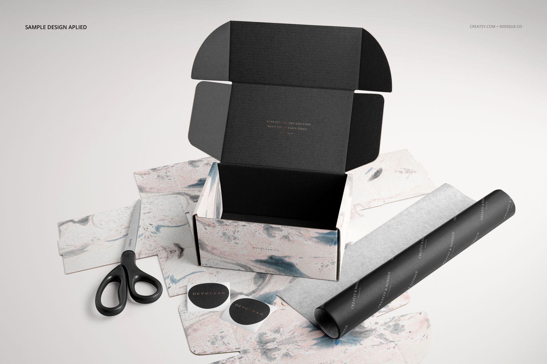 Front view of a mockup set featuring an open mailing box, decorative sheets, black tissue paper, and scissors.