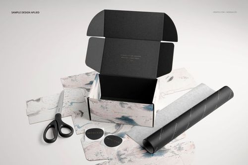 Front view of a mockup set featuring an open mailing box, decorative sheets, black tissue paper, and scissors.