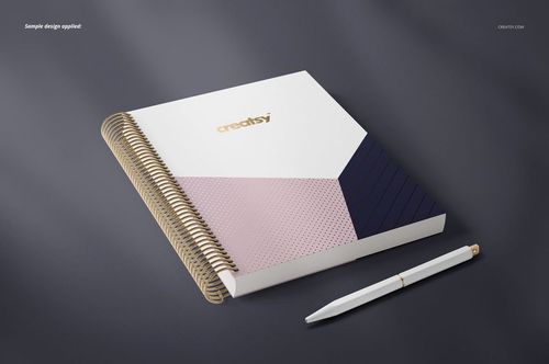 Spiral-bound planner mockup featuring a square cover with gold coil, geometric patterns, and a pen on a dark surface.