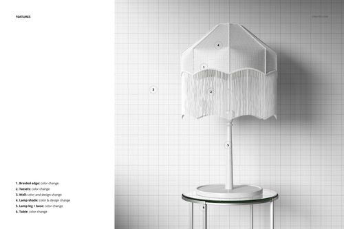 Front view of a tassel shade table lamp mockup with white braided edge and fringe, placed on a glass table against a grid wall.