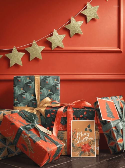 PSD mockup of multiple wrapped presents with gold and red ribbons, set beneath a gold star garland and greeting card.
