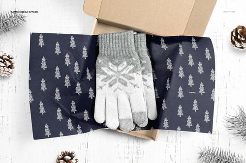 Mailer box mockup with navy tissue paper decorated with small white trees, gray snowflake gloves displayed inside.