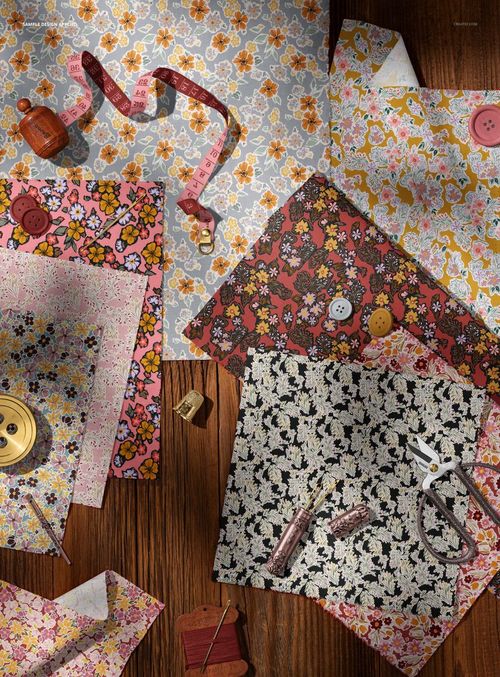 Vintage sewing setup featuring floral cotton fabric mockup, measuring tape, thread, and buttons from above.