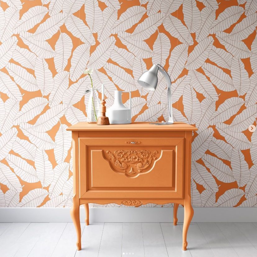 Interior scene mockup showing an orange vintage cabinet against a wall with a bold orange and white leaves pattern design.
