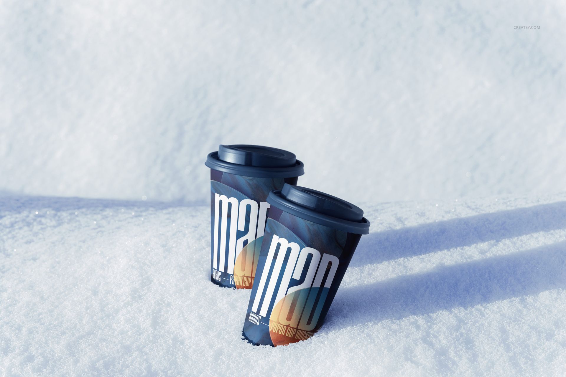 Winter paper cups mockup featuring two cups with graphic patterns and dark lids set on fresh white snow.
