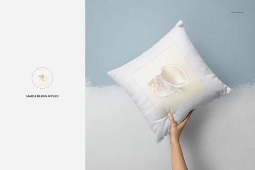 Mockup of a white polyester pillow with a custom design, displayed in a home setting with a hand holding it.