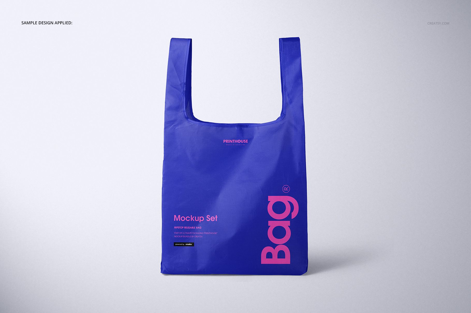 Reusable shopping bag mockup in blue, featuring bold pink lettering and a simple, minimalist studio setting.