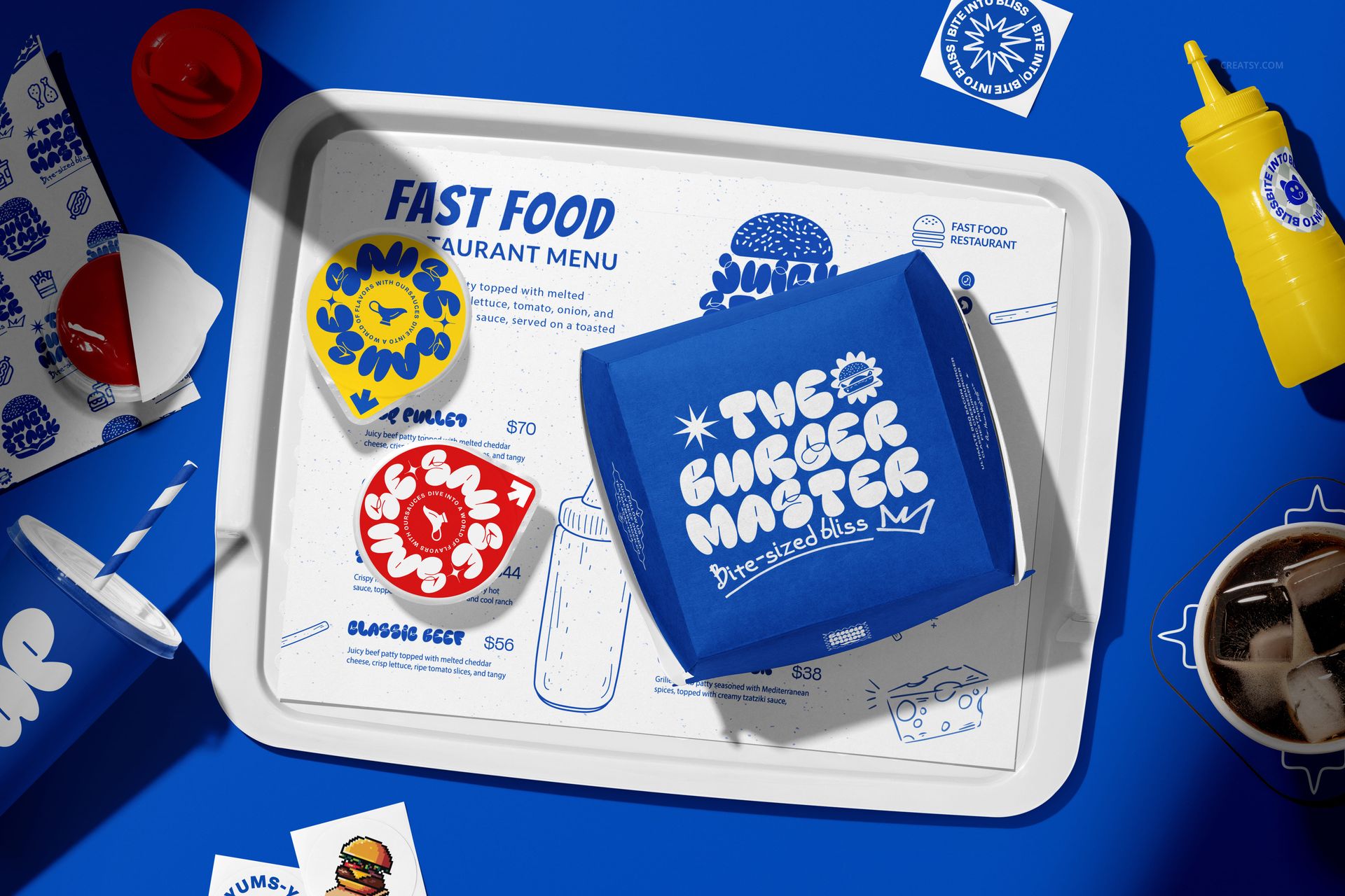 Front view of vegan burger bar packaging mockup with blue and red boxes, cups, and branded tray on blue surface.