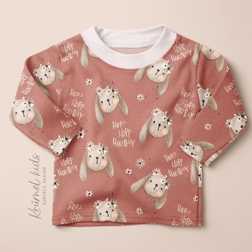 Baby and toddler long sleeve shirt mockup featuring a pink animal pattern with cartoon bunnies and white collar on beige background.