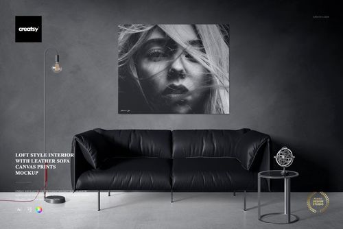 Front view of a loft style interior featuring a black leather sofa, gray wall, and canvas print mockup above the couch.