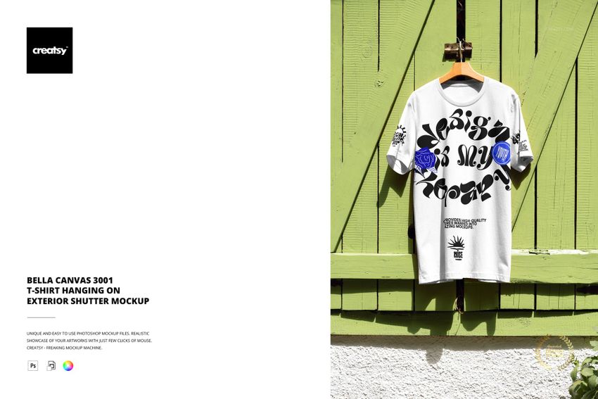 PSD mockup featuring a white short sleeve t-shirt with graphic elements, hung on a rustic green shutter outdoors.
