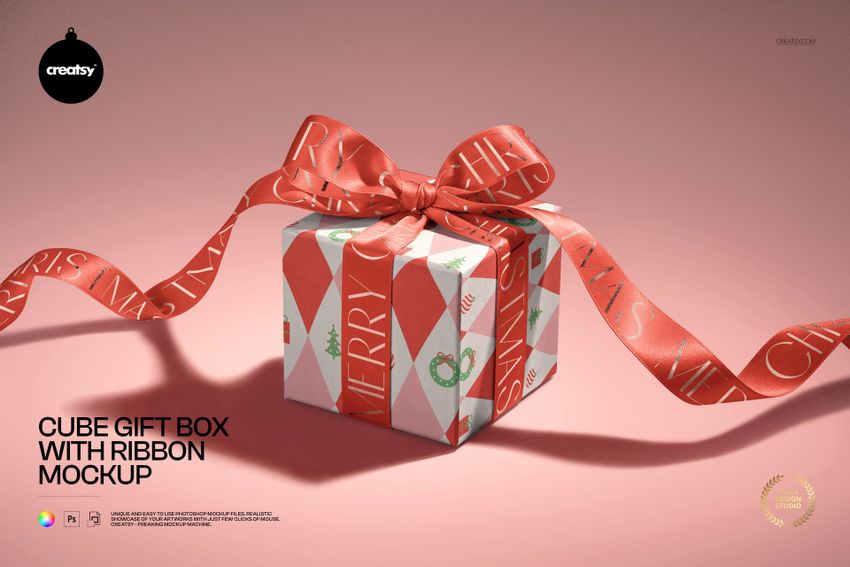 Front view of a cube-shaped gift box mockup with a decorative red ribbon and festive geometric design on a pink surface.