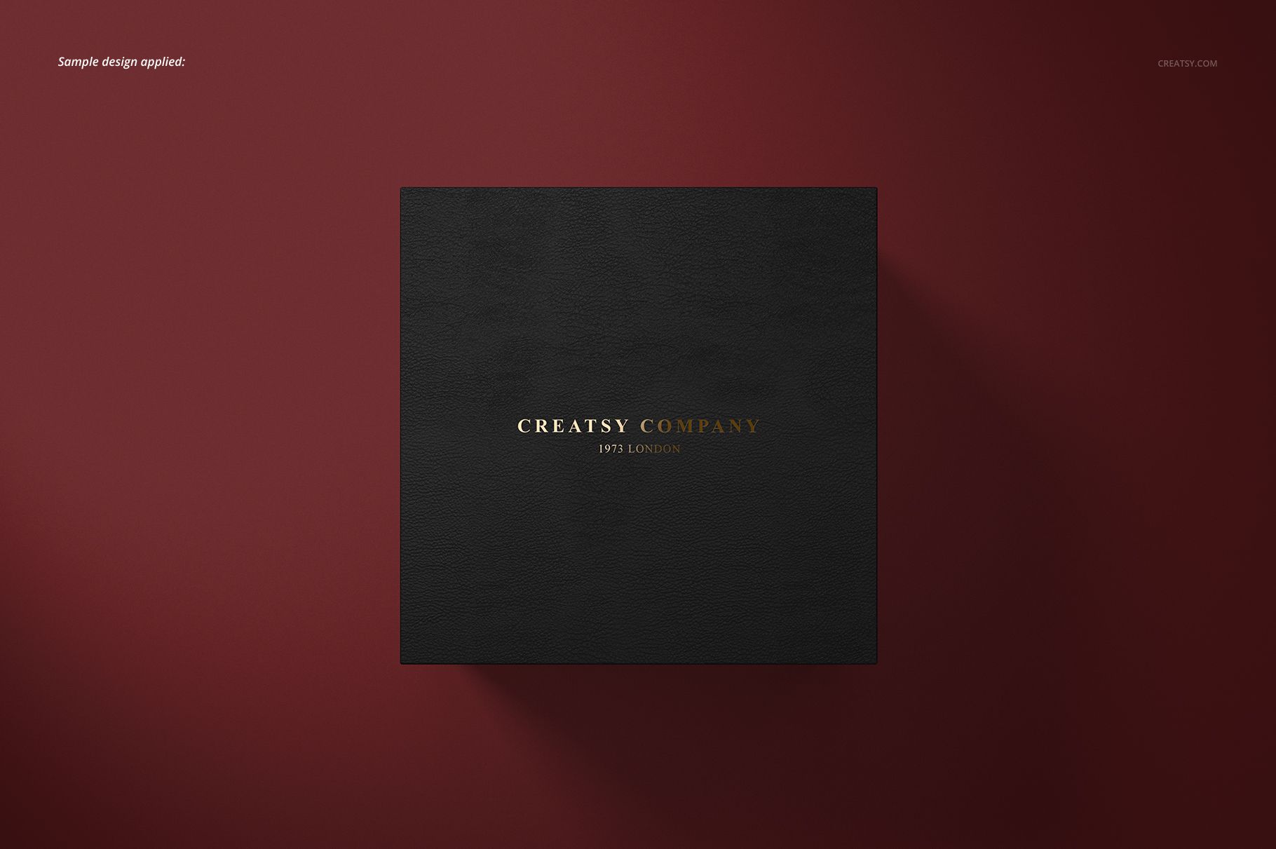 Black square cufflinks box with gold and white text, centered on a dark red background, top view mockup.