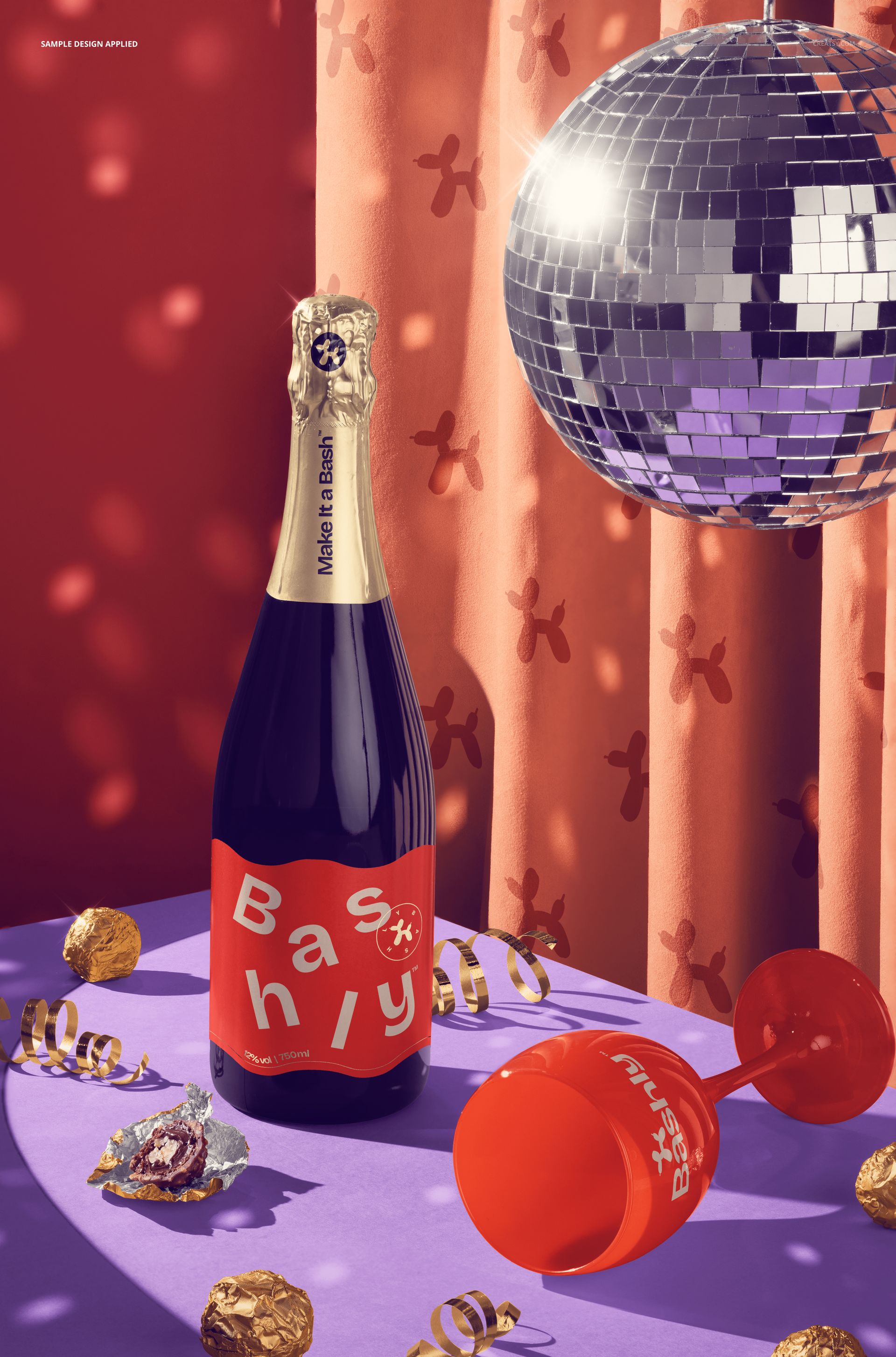 PSD mockup scene with upright champagne bottle, scattered pralines, ribbons, red wine glass, and mirror disco ball under party lights.
