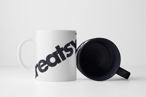 PSD mockup featuring two mugs, one standing with a graphic design and the other positioned to display its dark inside.