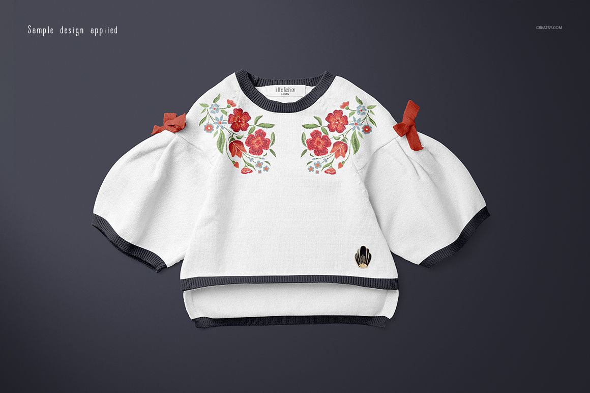 Front view of a baby sweater mockup with white fabric, floral red and green design, and dark trim on sleeves and hem.