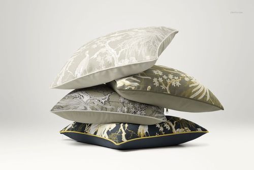 PSD mockup showing a pile of reversible cushions featuring detailed plant and animal motifs in muted and dark tones.