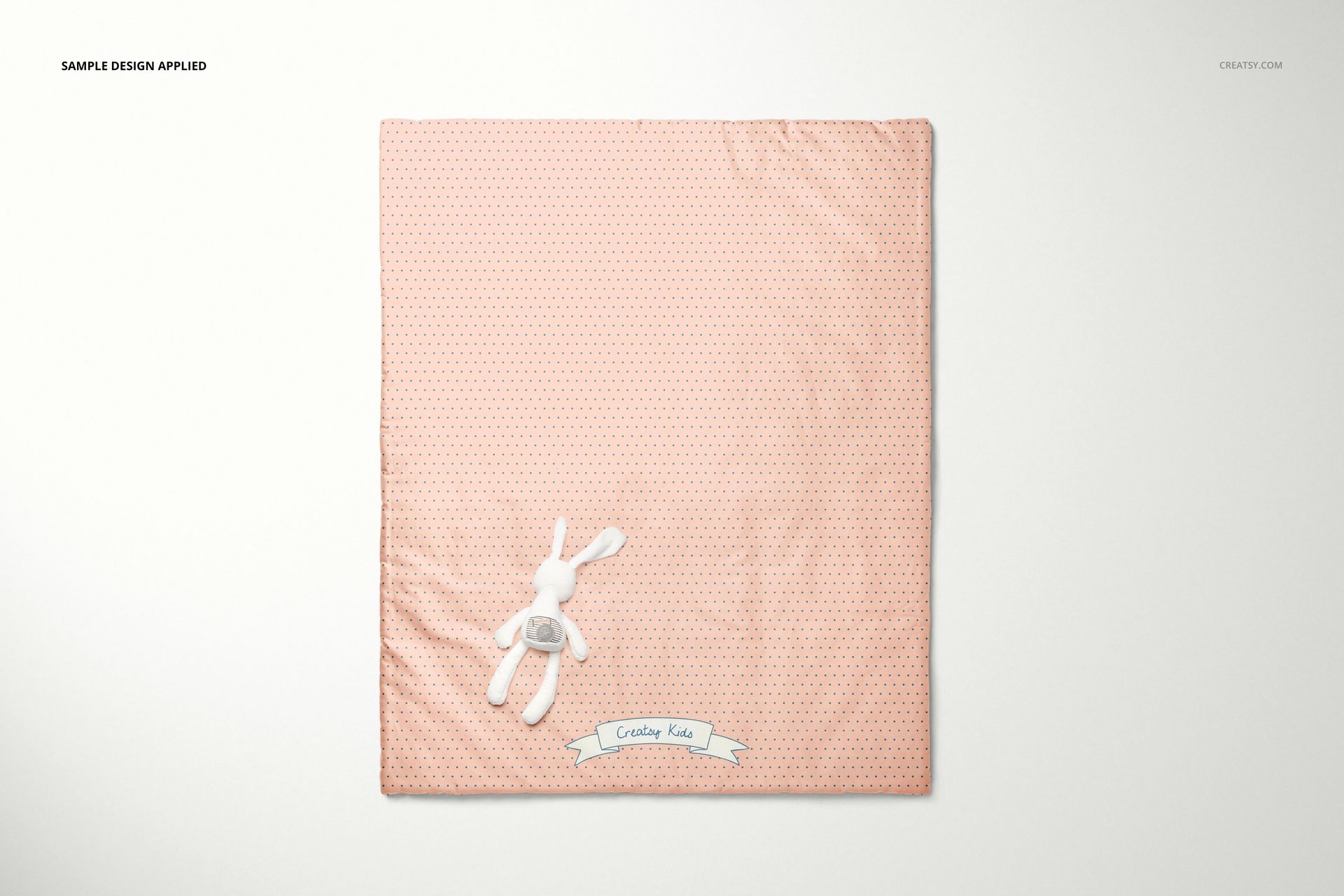 Baby patchwork quilt mockup shown flat on a light background, pink fabric with tiny dots and a stuffed bunny accent.