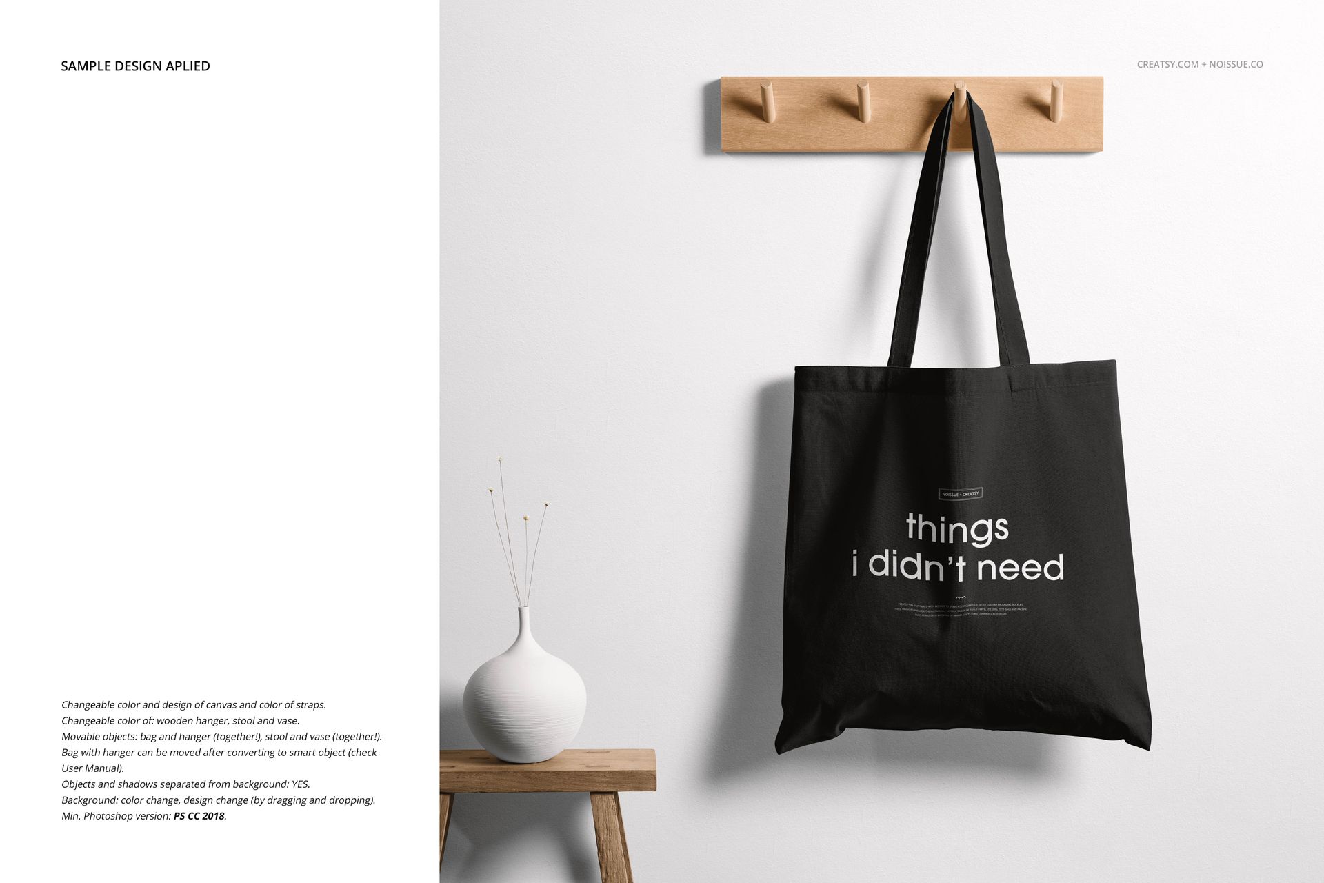 Front view of a black tote bag mockup with white text, hung on a wooden rack against a white wall.