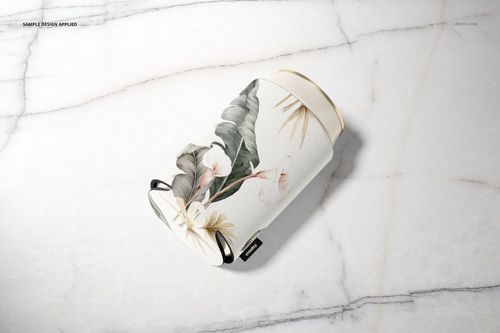 PSD mockup of a neoprene can cooler featuring a botanical design, displayed on a light marble background.