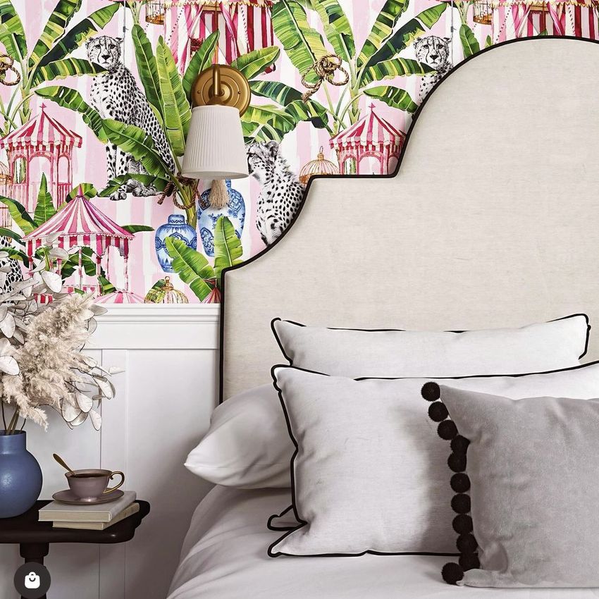 Bedroom mockup featuring a light upholstered headboard, white pillows with black trim, and wallpaper with tropical leaves and leopards.