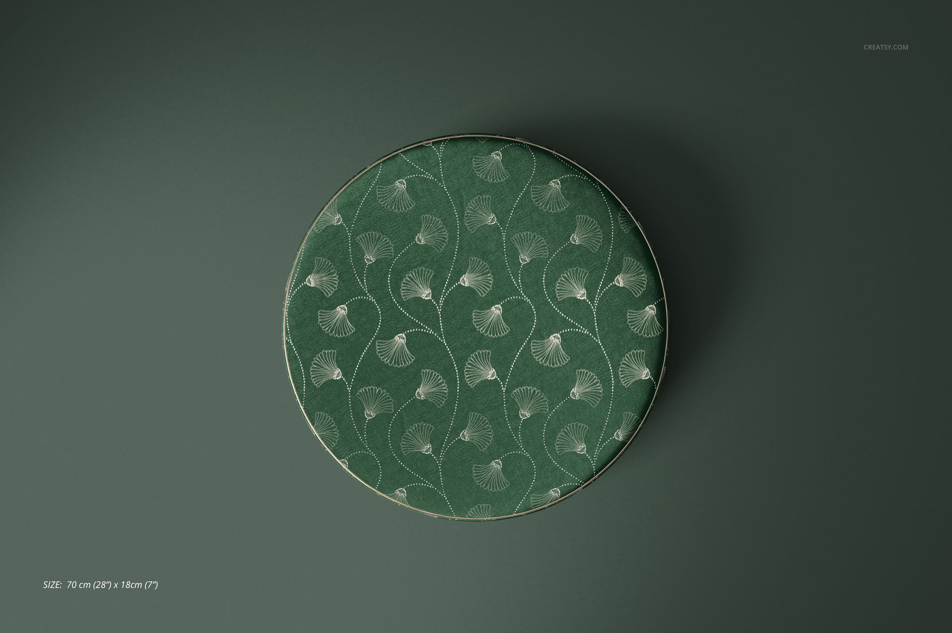 Mockup of a round pouf upholstered in green velvet with a subtle leaf motif, presented on a plain green surface.