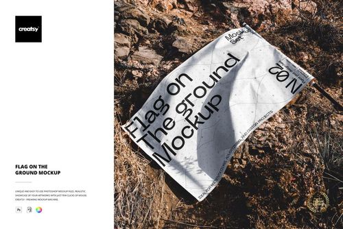 White flag mockup with bold black lettering placed on uneven rocks, viewed from above in a natural outdoor setting.
