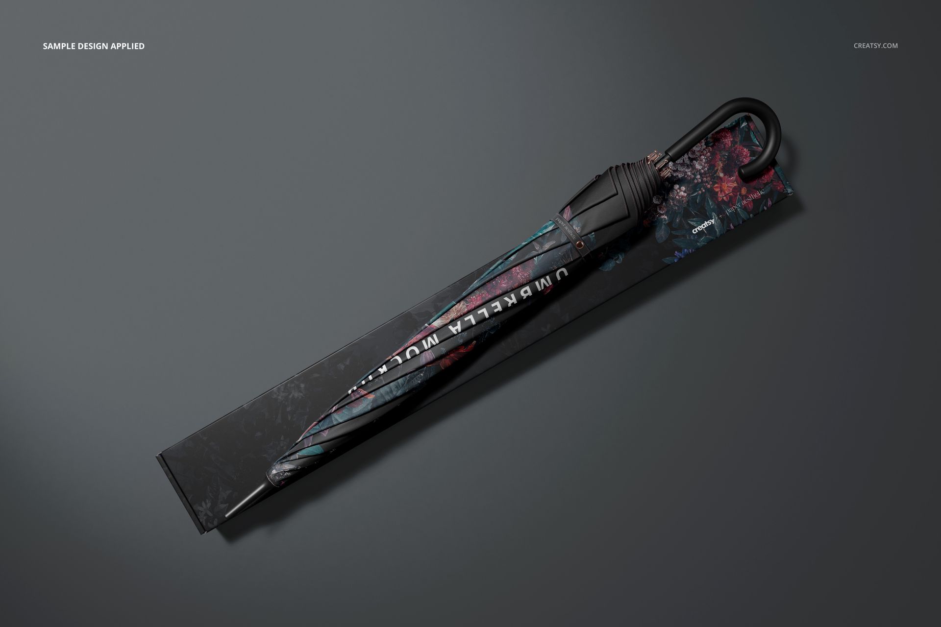 Umbrella featuring a black handle and colorful design, resting on coordinating packaging in a top-down mockup scene.
