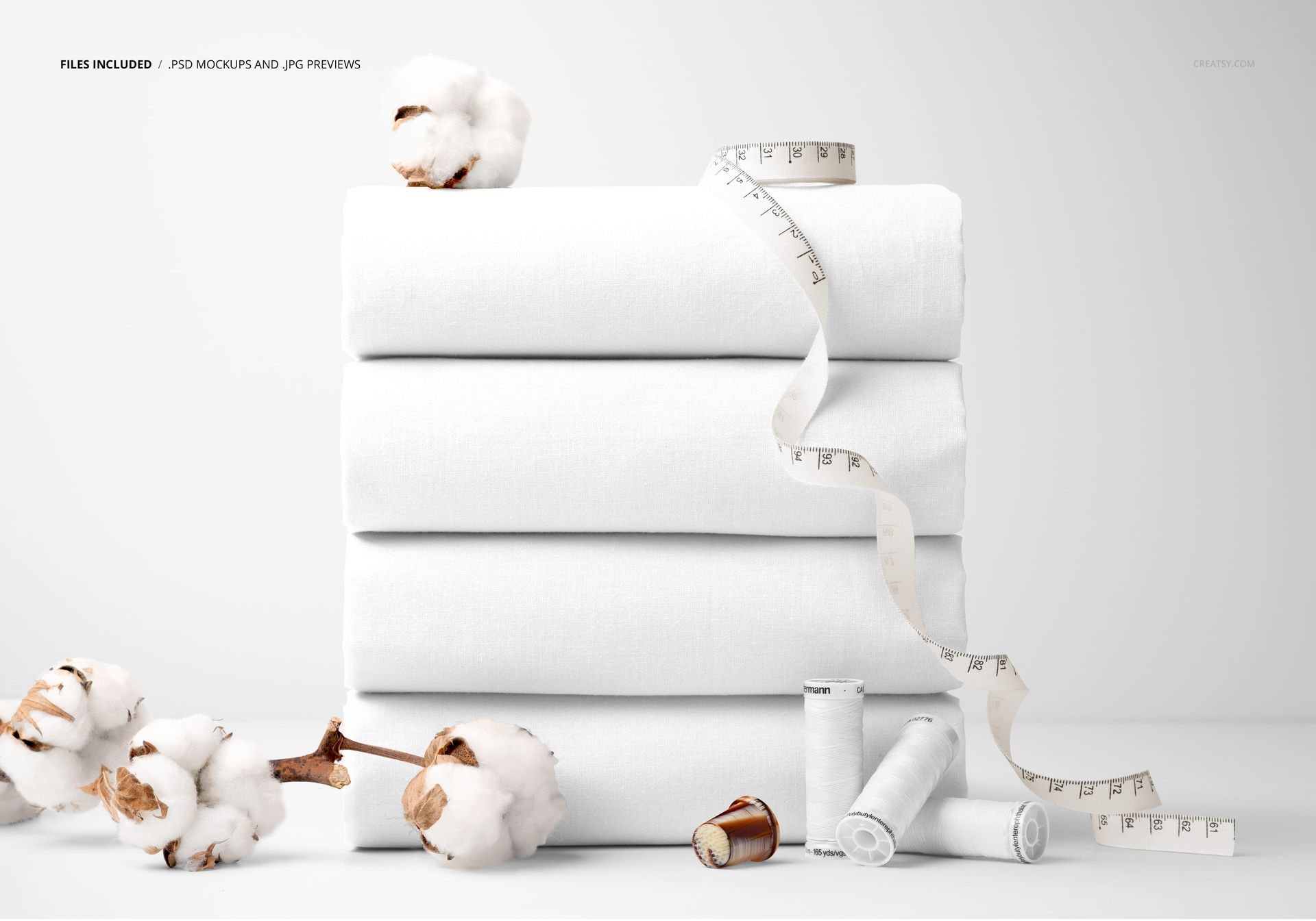 PSD mockup showing a pile of white cotton fabrics alongside sewing props like cotton branches, thread spools, and measuring tape.