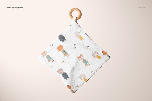PSD mockup of a square muslin swaddle with wooden teether, showing whimsical animal designs against a neutral background.