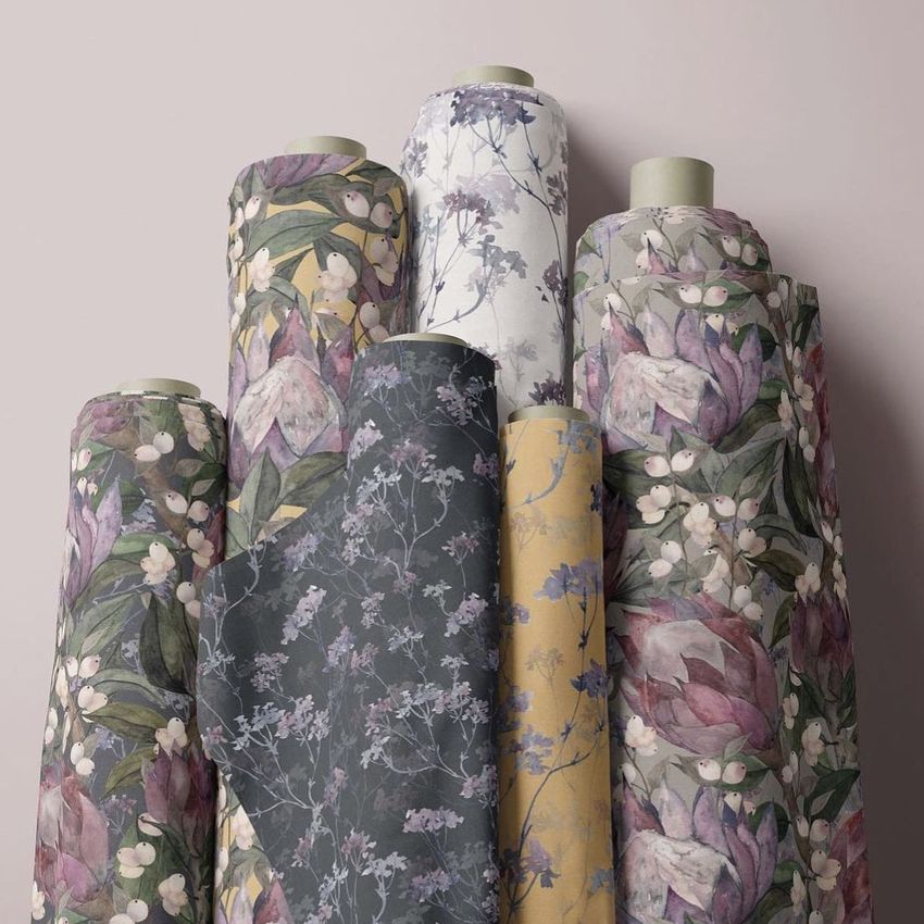 Fabric rolls mockup featuring six upright rolls with botanical patterns in muted tones, arranged against a pale background.