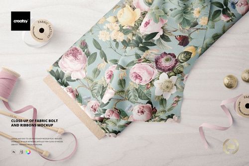 Fabric bolt mockup featuring a detailed flower print in soft tones, accompanied by pink ribbons and beige thread spools on a table.