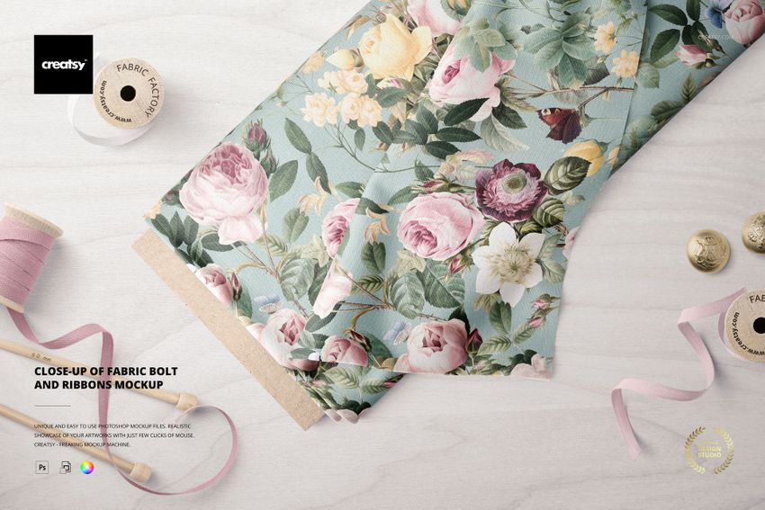 Fabric bolt mockup featuring a detailed flower print in soft tones, accompanied by pink ribbons and beige thread spools on a table.