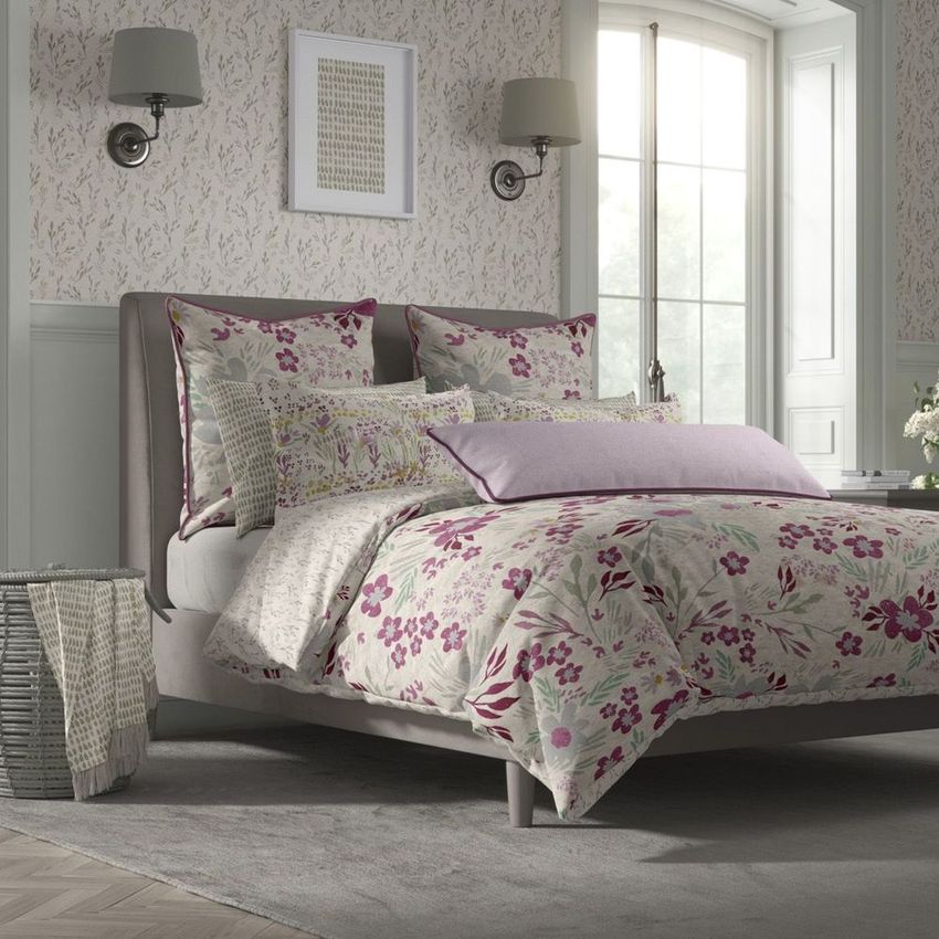Cottage style bedroom bedding mockup featuring a bed with floral-patterned sheets and pillows in purple and cream tones.