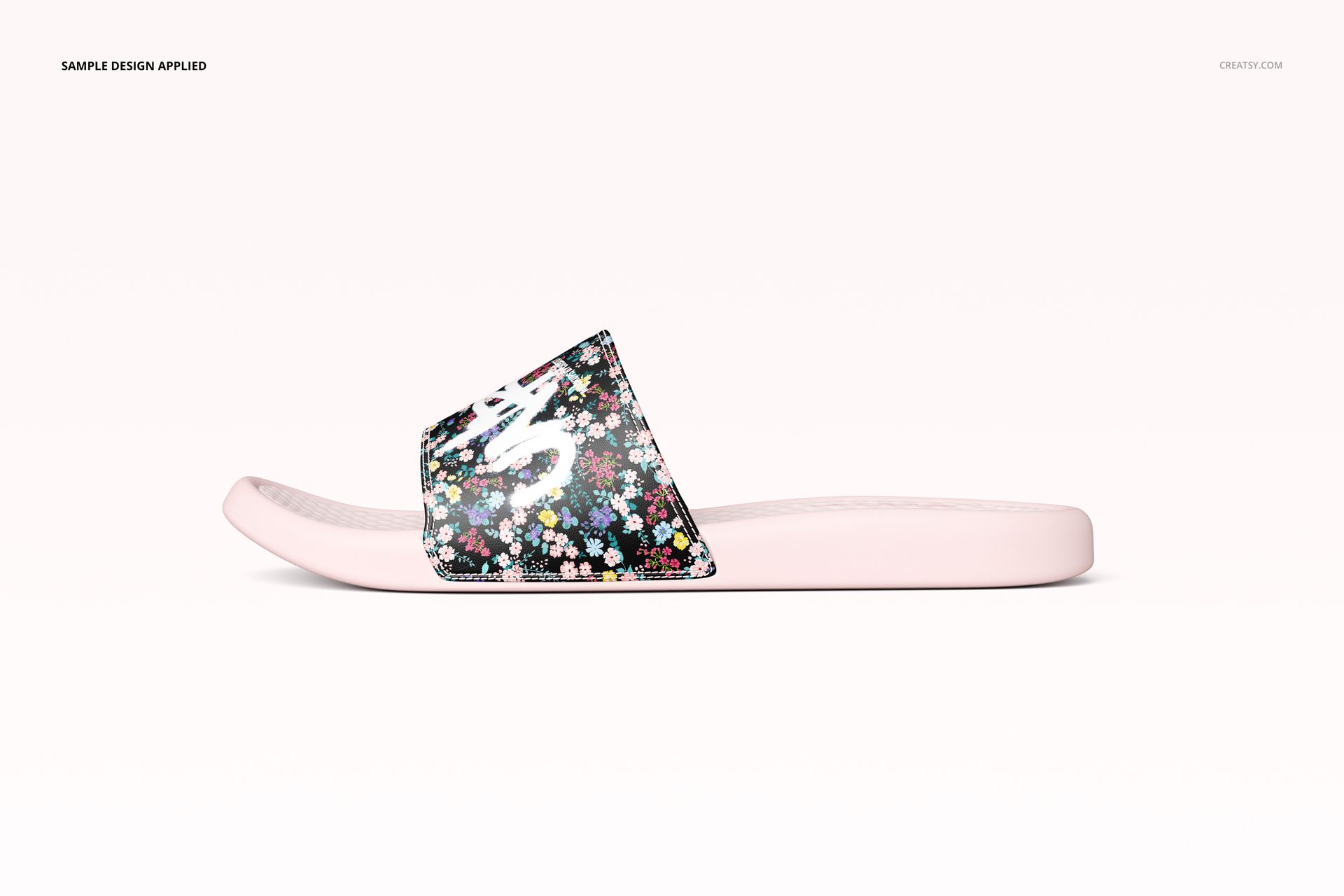 Side view of a slide sandal mockup with a light pink sole and a strap featuring a colorful floral pattern.