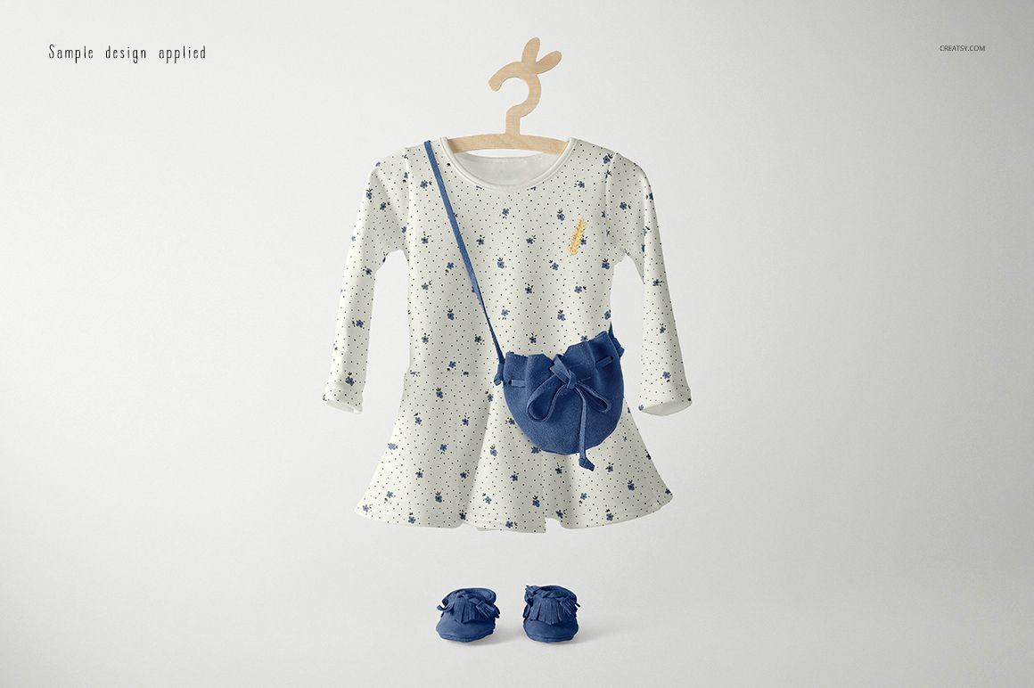 Long-sleeve baby dress mockup with a white base and blue star pattern, displayed with matching blue bag and shoes.
