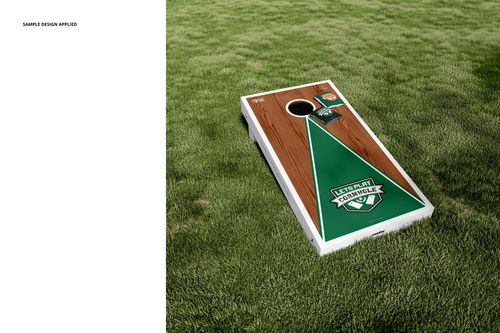 Cornhole board and bean bags mockup on green grass, featuring wood texture and green geometric design.