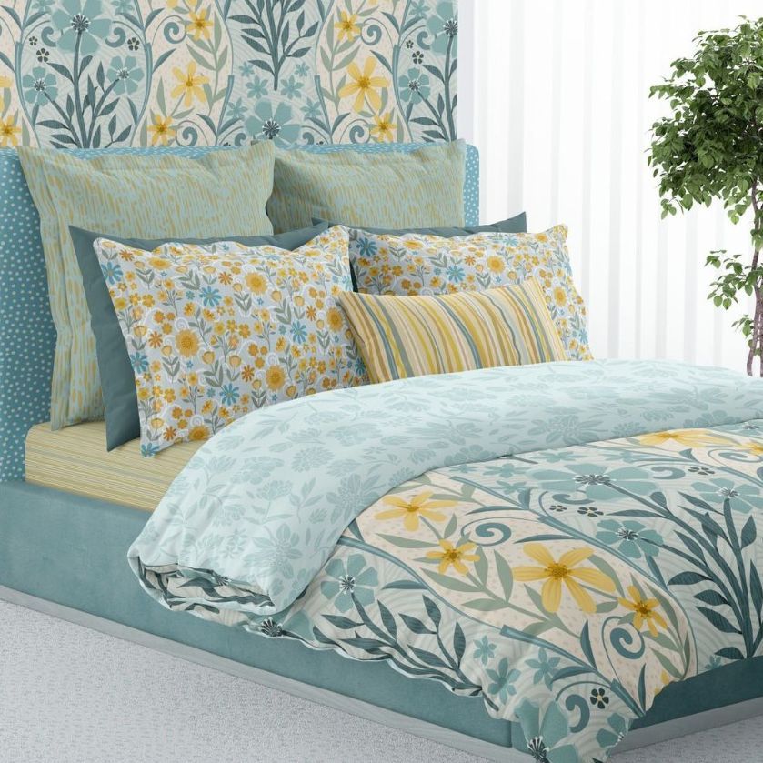 Bedroom scene bedding mockup showing a made bed with patterned duvet, pillows, and headboard in blue, yellow, and white tones.
