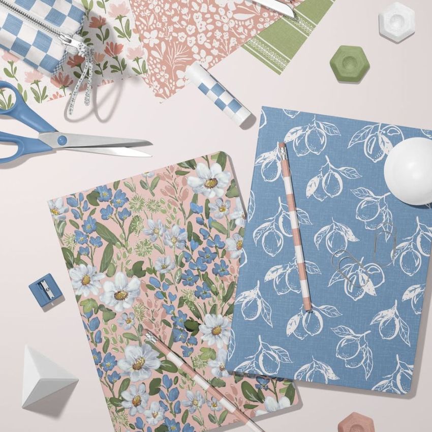 Stationery mockup featuring two classic A4 notebooks with floral covers, surrounded by pens, scissors, and patterned paper.