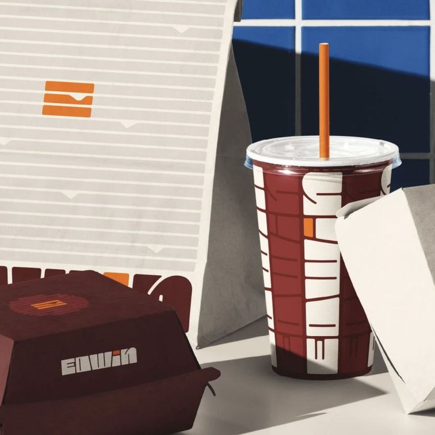 Burger packaging mockup featuring a paper bag, drink cup with straw, and food containers with geometric patterns and text.