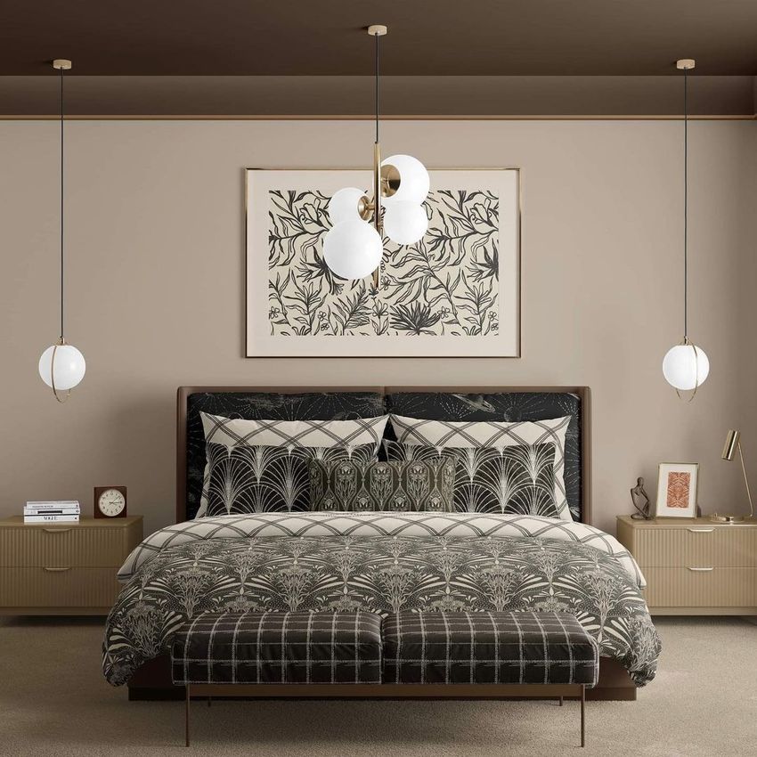 Bedroom scene bedding mockup showing a neatly made bed with patterned duvet and pillows, flanked by two nightstands and pendant lights.