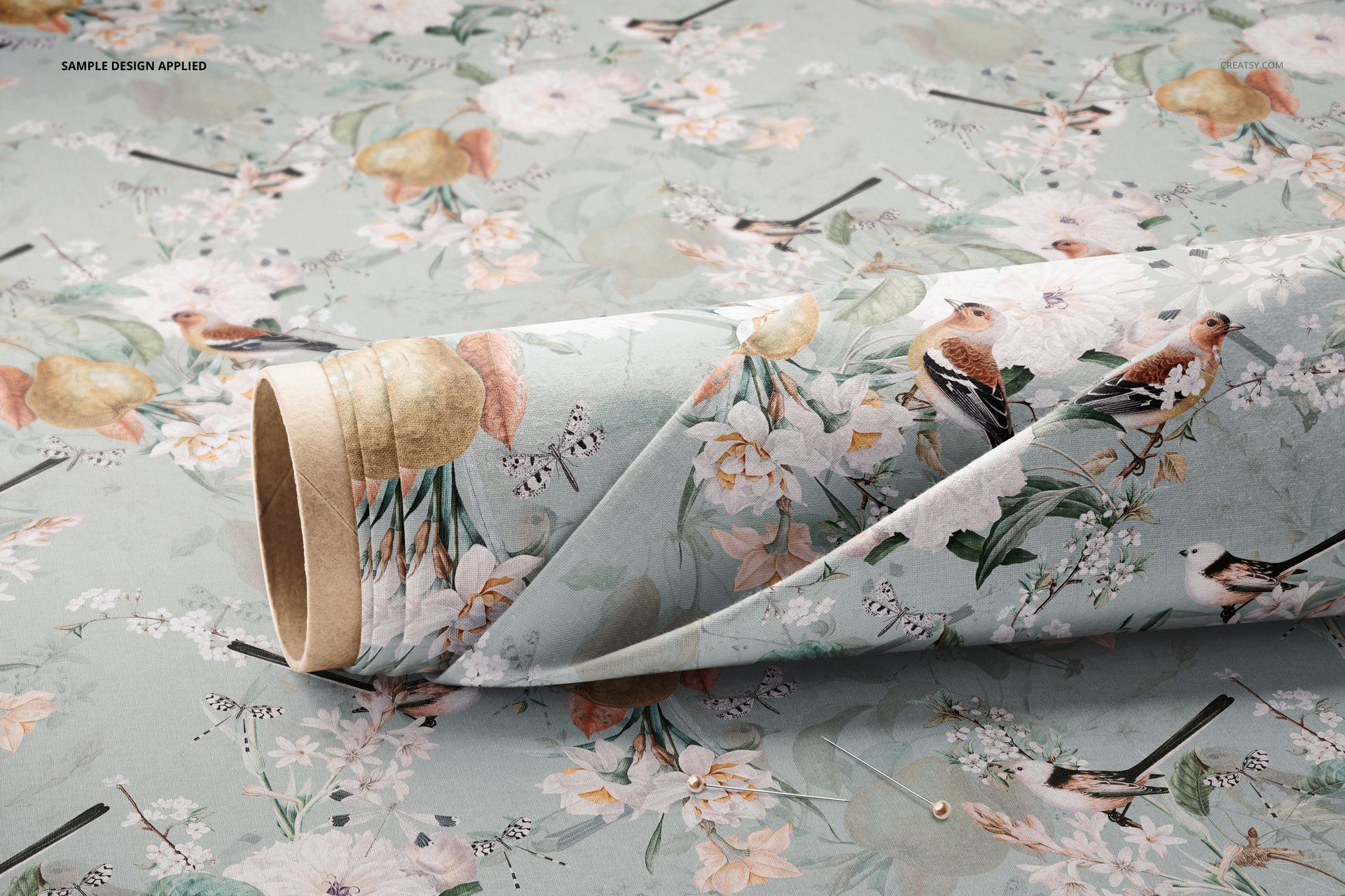 PSD mockup of a fabric roll with a botanical and bird design, viewed from the side and surrounded by similar printed fabric.