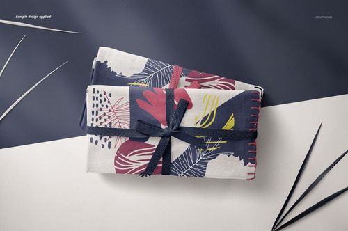PSD mockup of folded linen fabric with bold brushstroke pattern in blue, red, and white, tied with a ribbon.