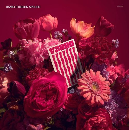 Greeting card mockup displayed within a vibrant flower bouquet featuring pink, red, and coral blossoms on a deep magenta background.