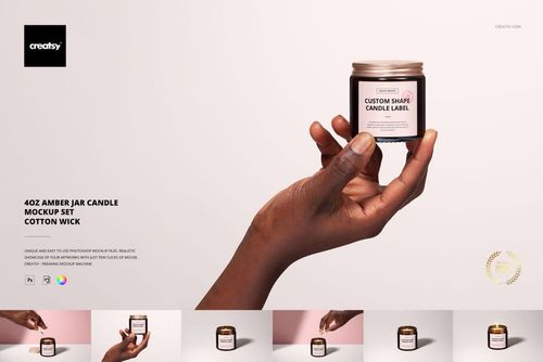 Front view of an amber jar candle with cotton wick, held by a hand, with mockup label on a neutral backdrop.