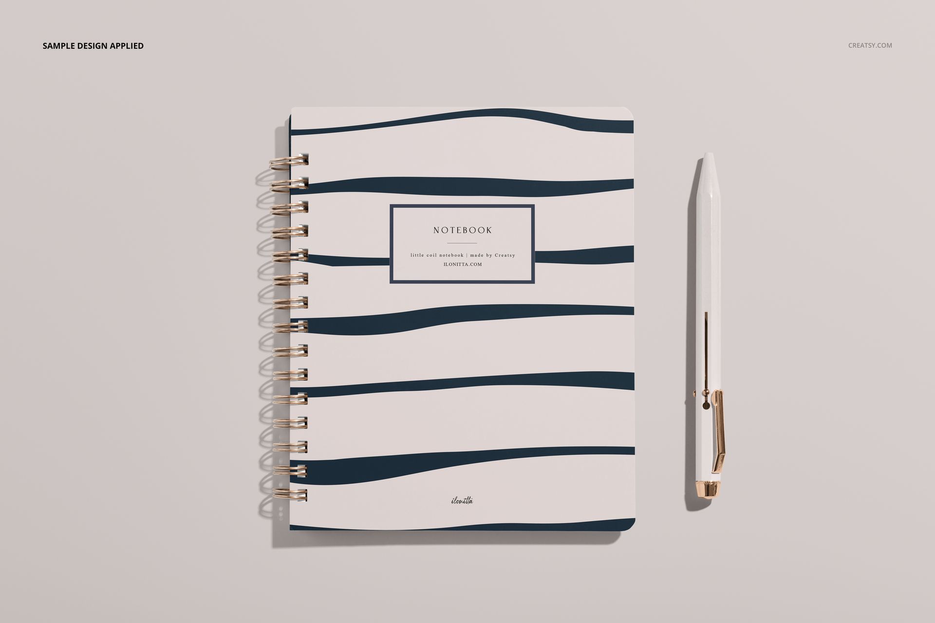 Little coiled notebook mockup showing a white cover with dark blue wave pattern, spiral binding, and a pen beside it.