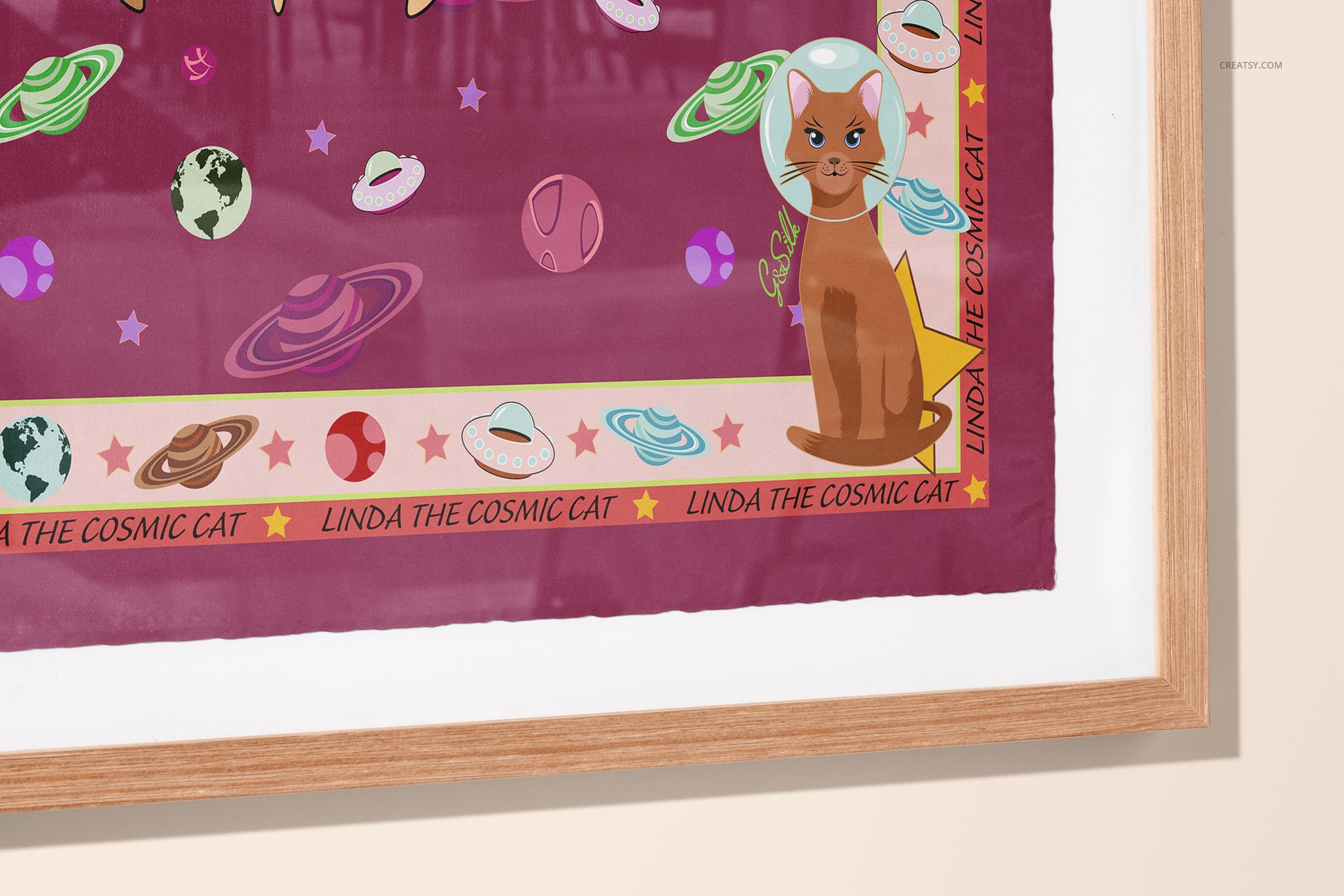 Square silk scarf featuring planets, stars, and a cat motif, presented as a PSD mockup in a wooden frame.